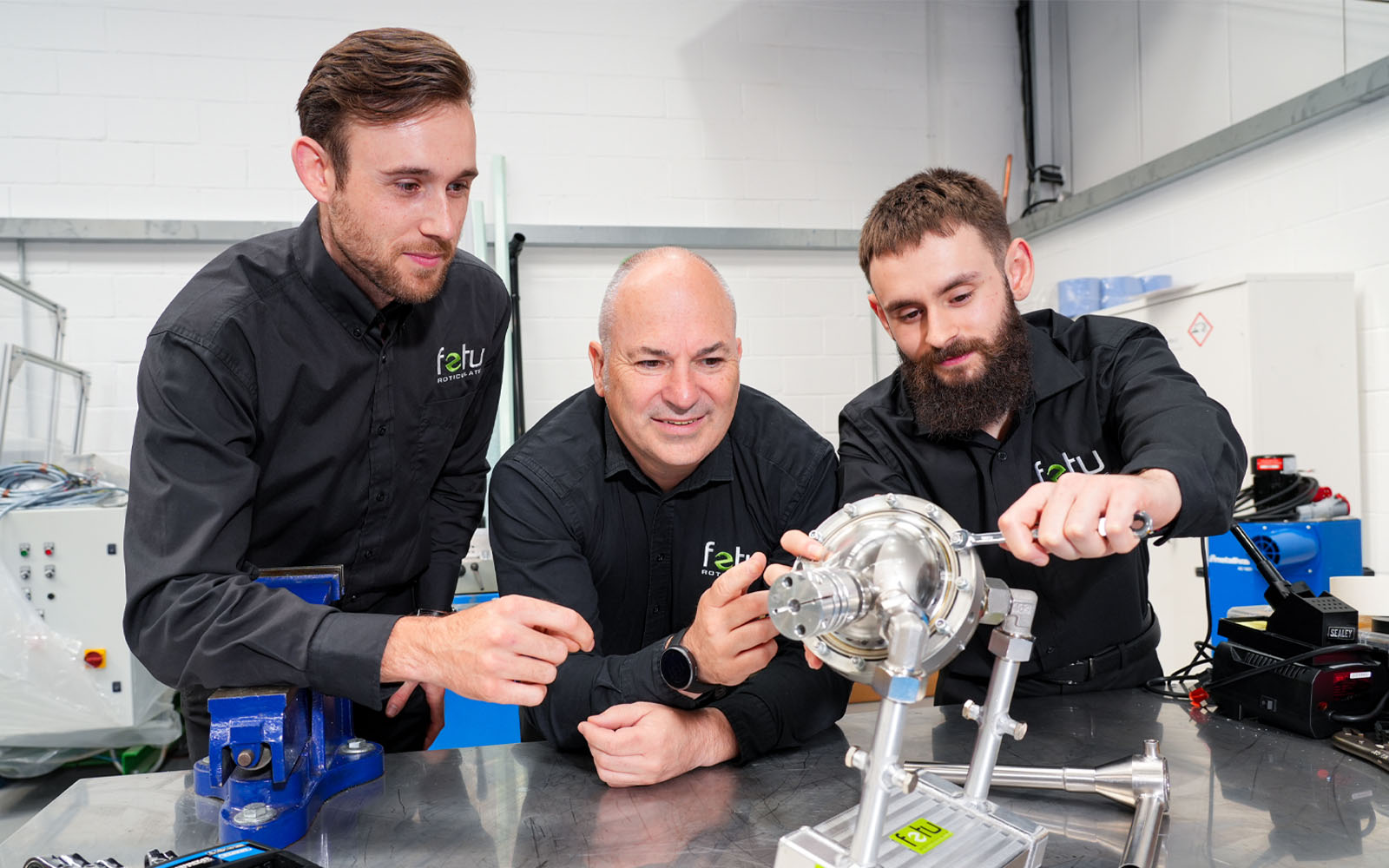 Three men interacting with FeTu's heat pump